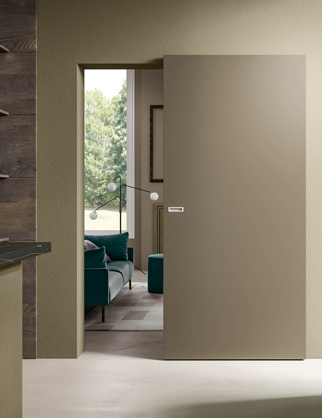 Dettaglio di un varco con un'elegante porta d'interno a battente laccata bianca, caratterizzata da tre pannelli bugnati in stile classico e cornici tradizionali, in un ambiente luminoso.