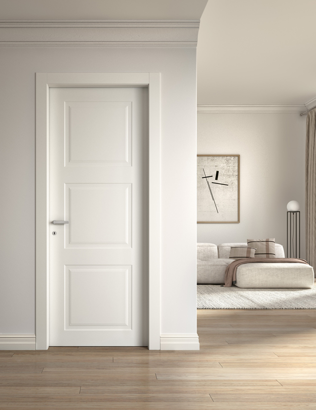 Dettaglio di un'elegante porta d'interno scorrevole esterno muro, con pannello liscio color tortora opaco, che divide l'ambiente da un moderno salotto con divano verde ottanio.