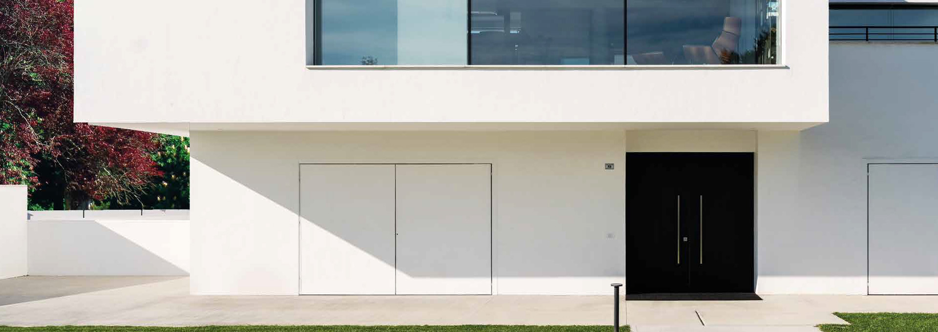 Portoni blindati Alias: soluzioni su misura per ingressi prestigiosi Esempio di porta blindata Alias a doppia anta nera con maniglioni verticali, installata come ingresso principale di una villa contemporanea bianca.