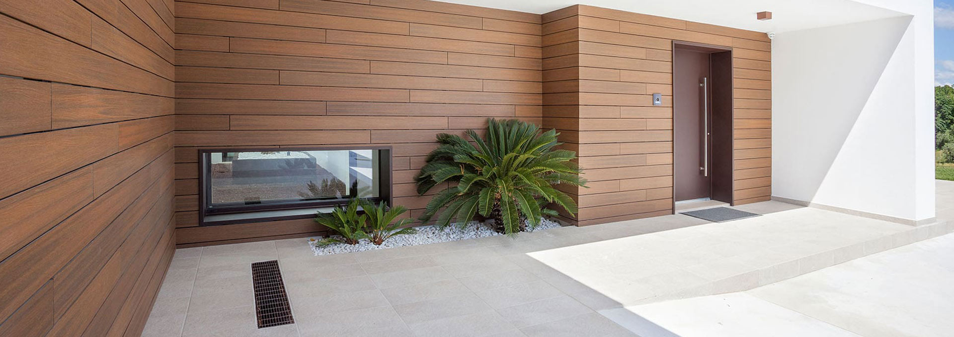 Rivestimenti di facciata Déco a Roma: resistenza e stile per l'outdoor Ingresso di una villa moderna con facciata rivestita in pannelli di legno composito WPC Déco a doghe orizzontali.