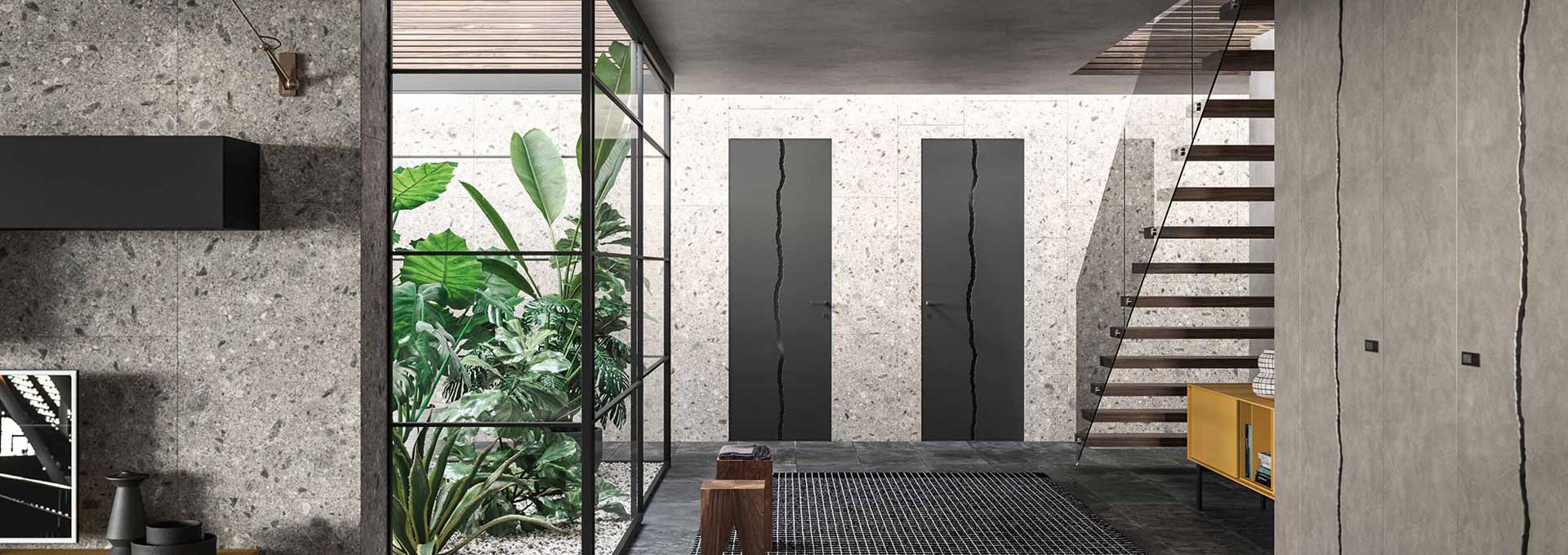 Eleganza senza tempo: porte battenti DoorArreda a Roma Porta battente DoorArreda color tortora opaco con telaio a vista, installata in un luminoso open space con grandi vetrate panoramiche sul parco.