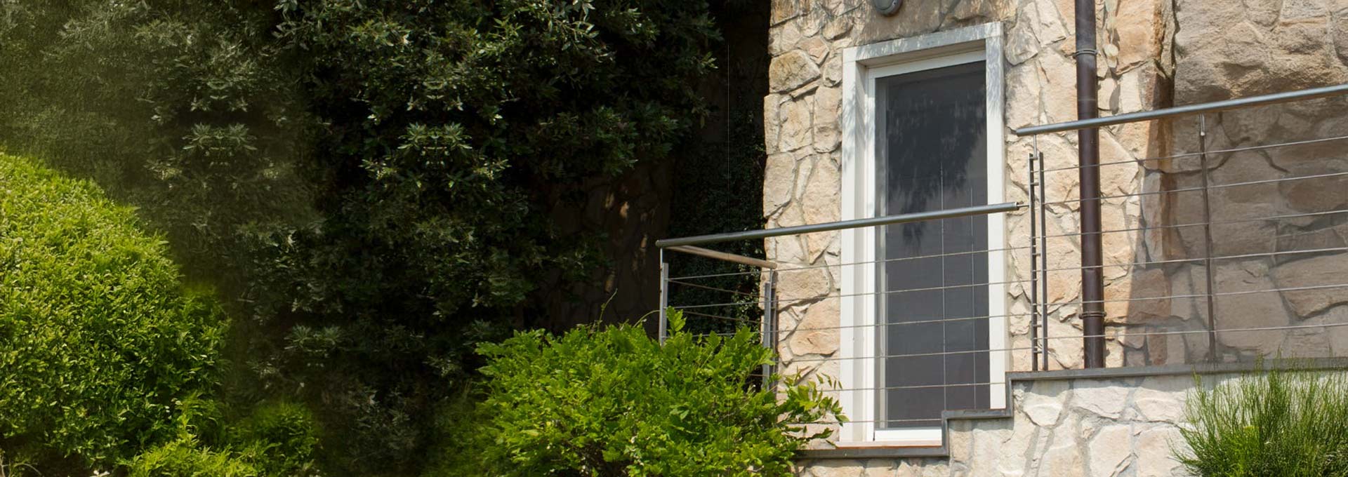 Installazione zanzariere Bettio a Roma: qualità e durata nel tempo Dettaglio esterno di una zanzariera Bettio installata su una finestra in una villa con facciata in pietra naturale, integrazione estetica perfetta.