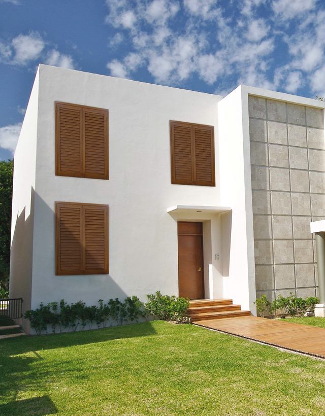 Facciata di una villa moderna intonacata di bianco con finestre dotate di persiane marroni effetto legno e porta d'ingresso coordinata.