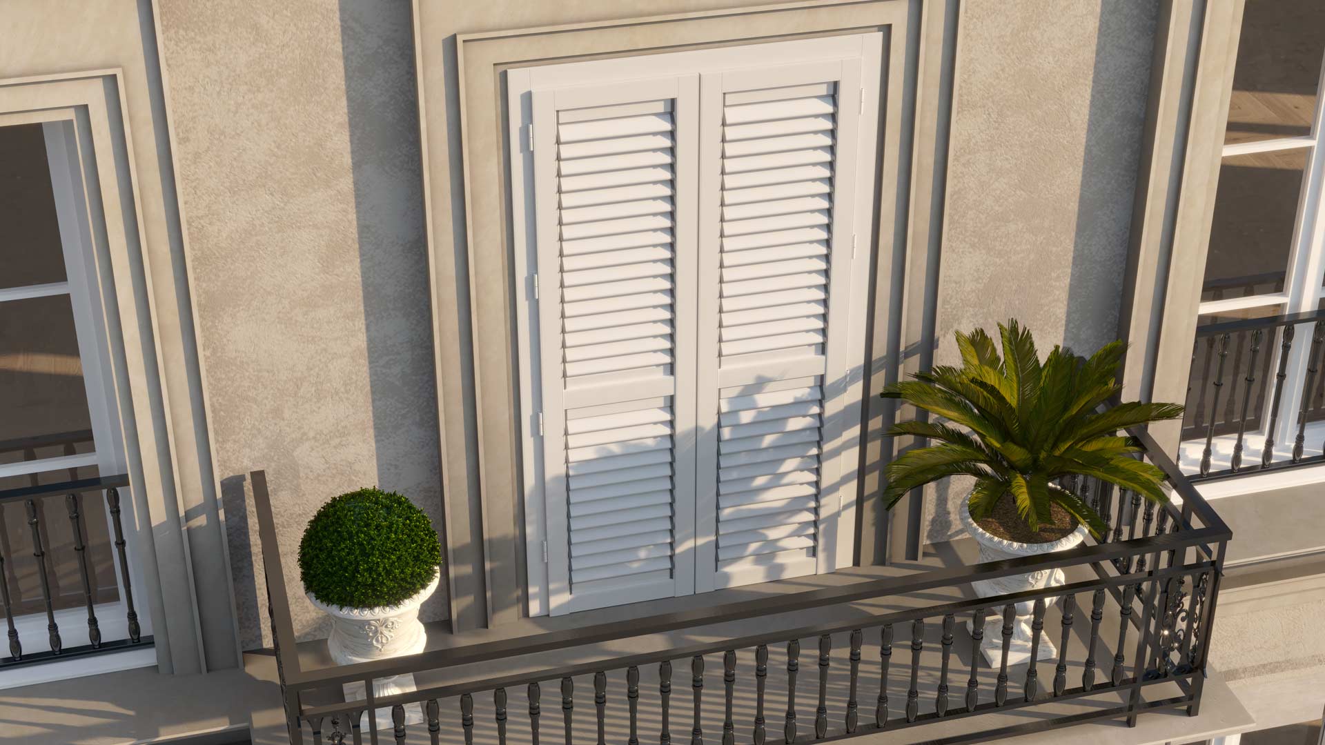 Elegante balcone d'epoca con ringhiera in ferro battuto e un'ampia portafinestra protetta da persiane tradizionali in alluminio verniciato di bianco, affiancate da vasi ornamentali.