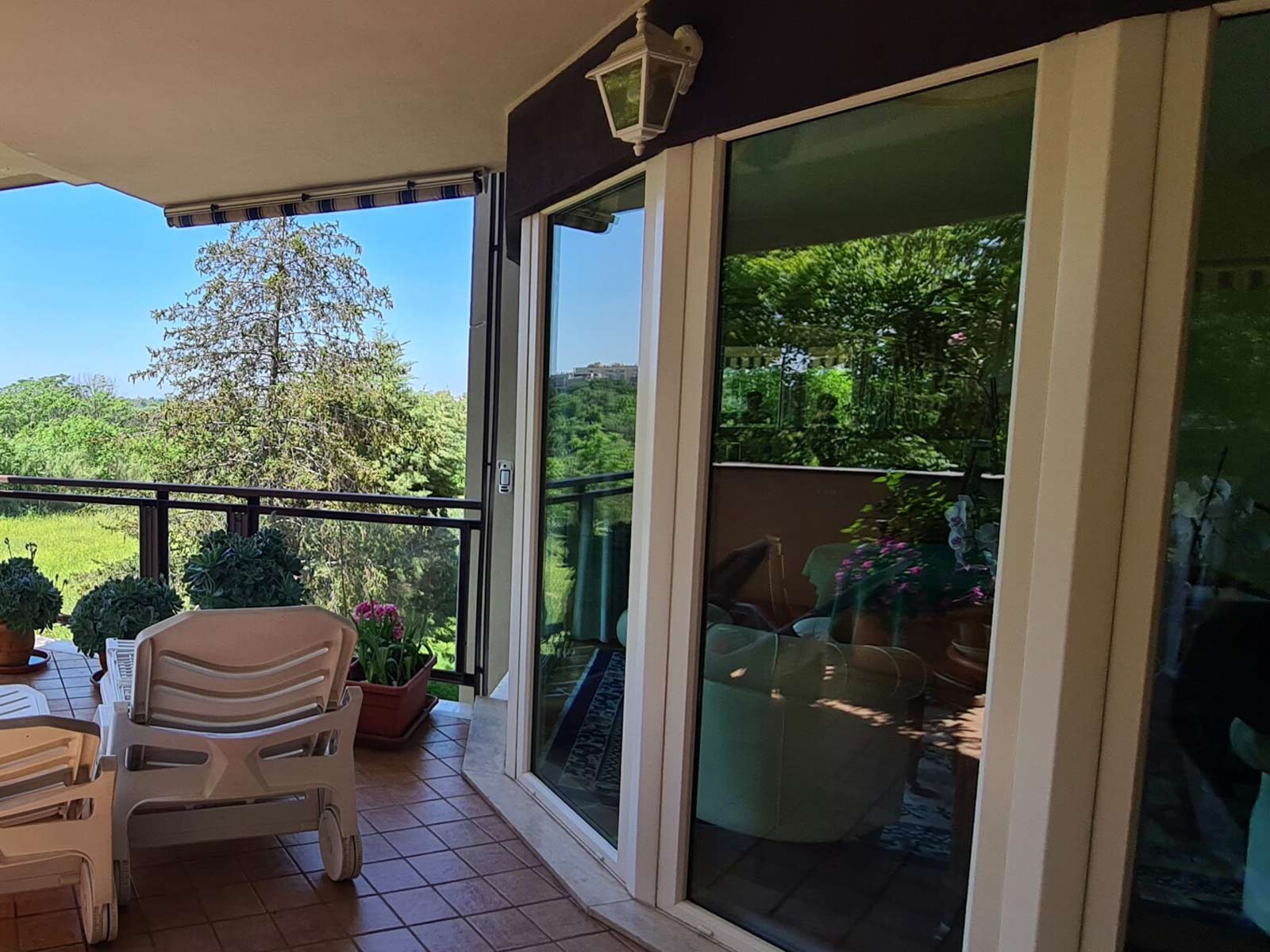 Grandi infissi scorrevoli bianchi che si affacciano su un terrazzo panoramico a Roma