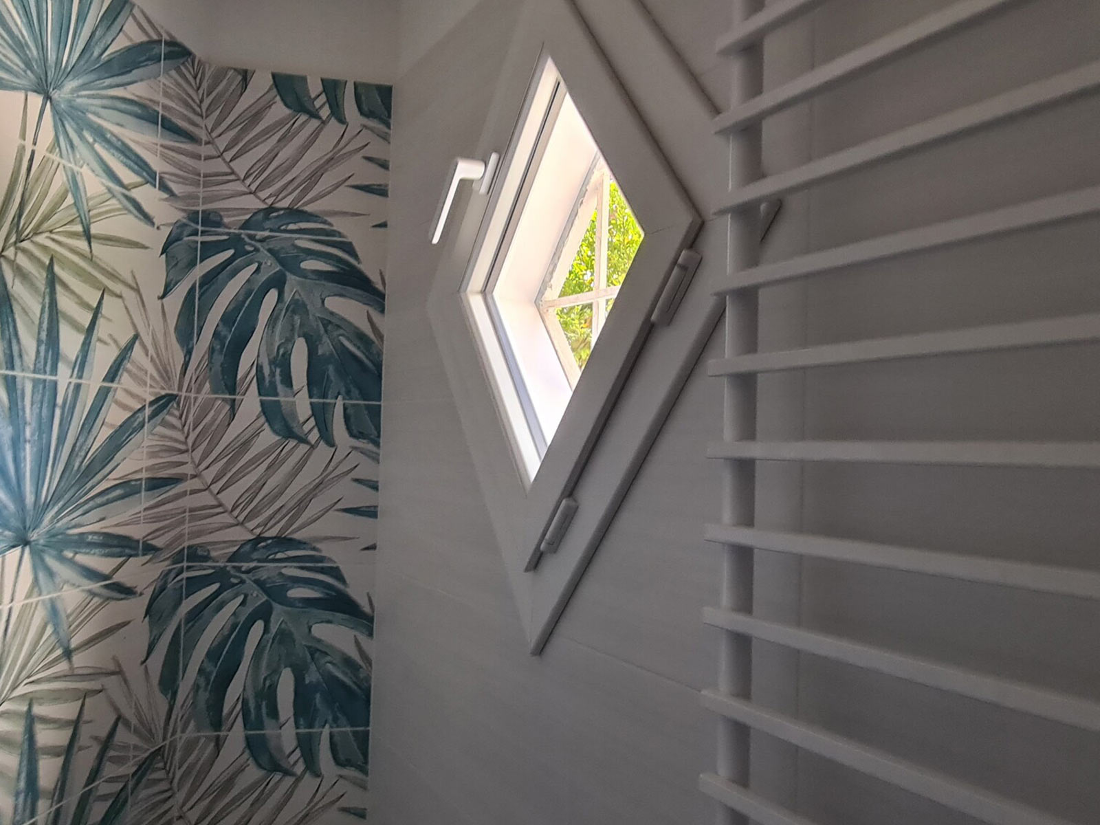 Finestra sagomata a forma di rombo installata in un bagno dal design moderno