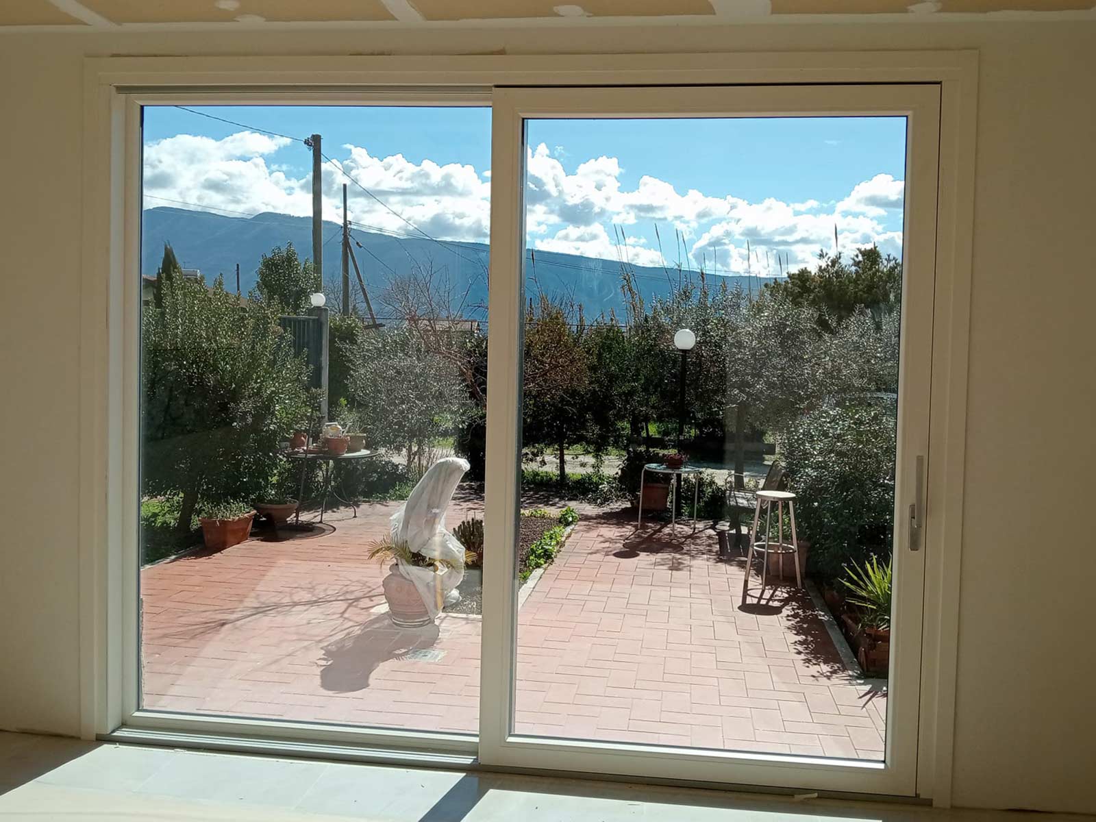 Grande infisso scorrevole in PVC bicolore aperto su un giardino ad Anagni