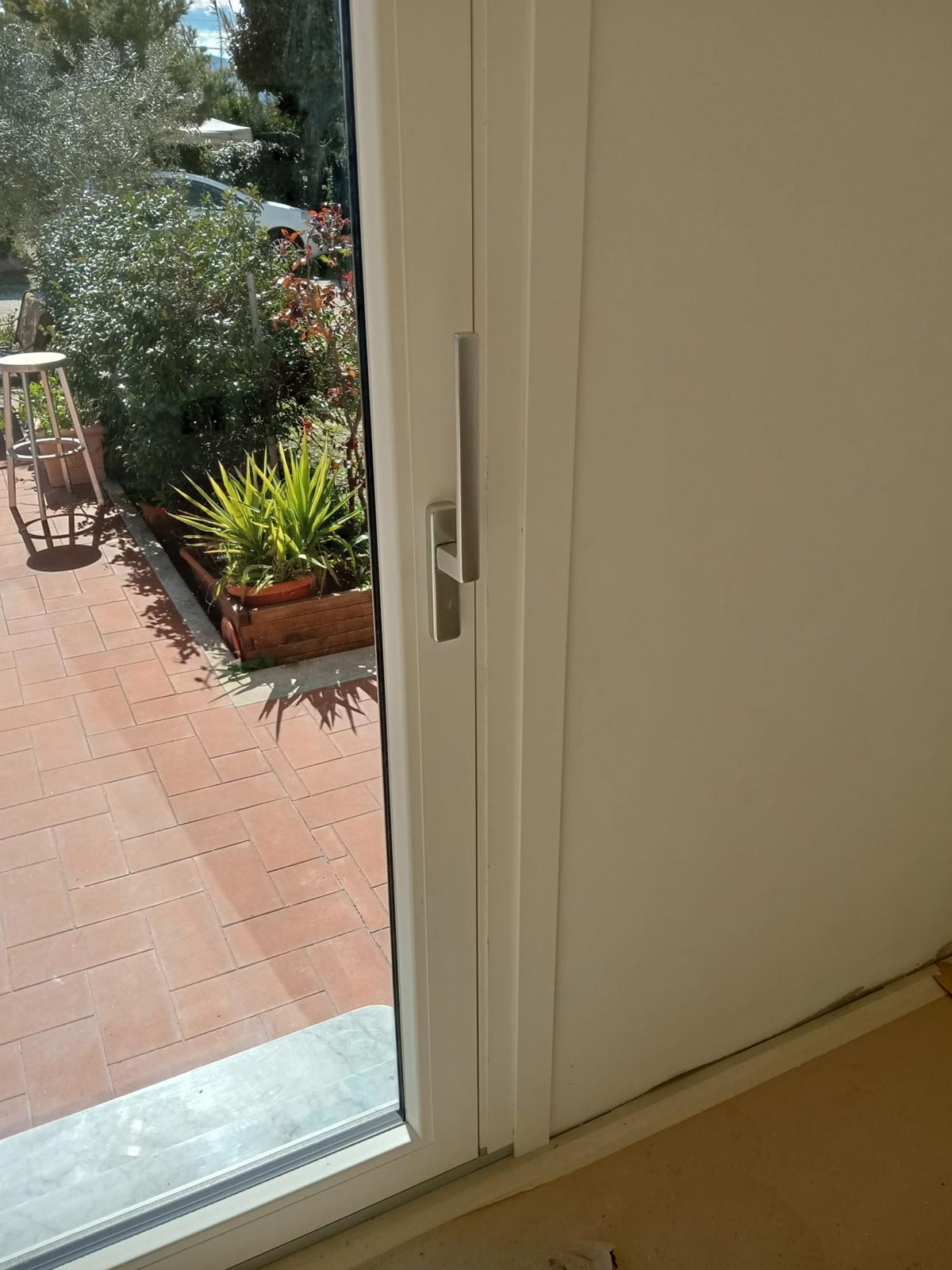 Dettaglio della maniglia di design su infisso scorrevole in PVC bianco