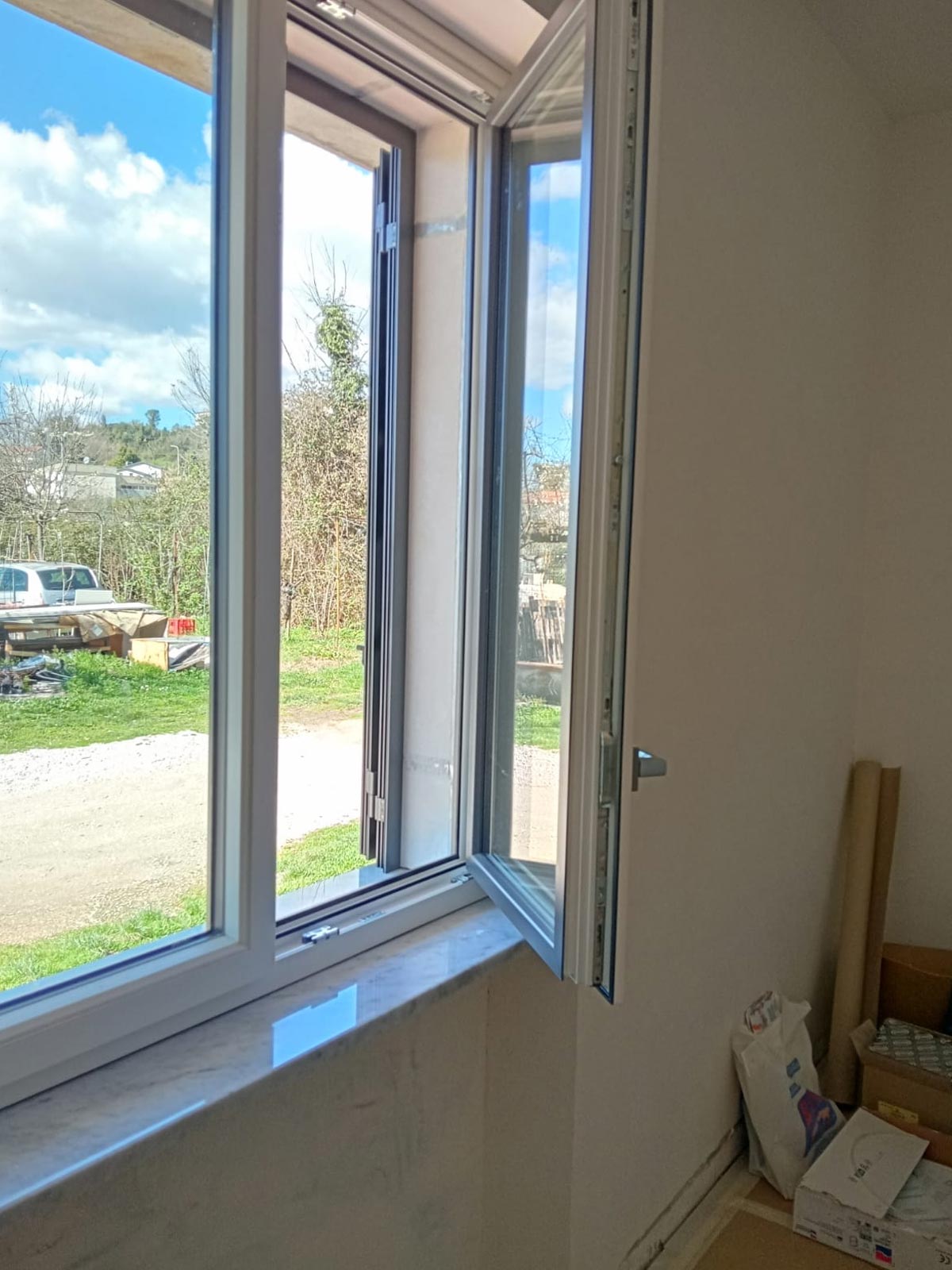 Finestra a battente in PVC bicolore aperta con vista sul giardino