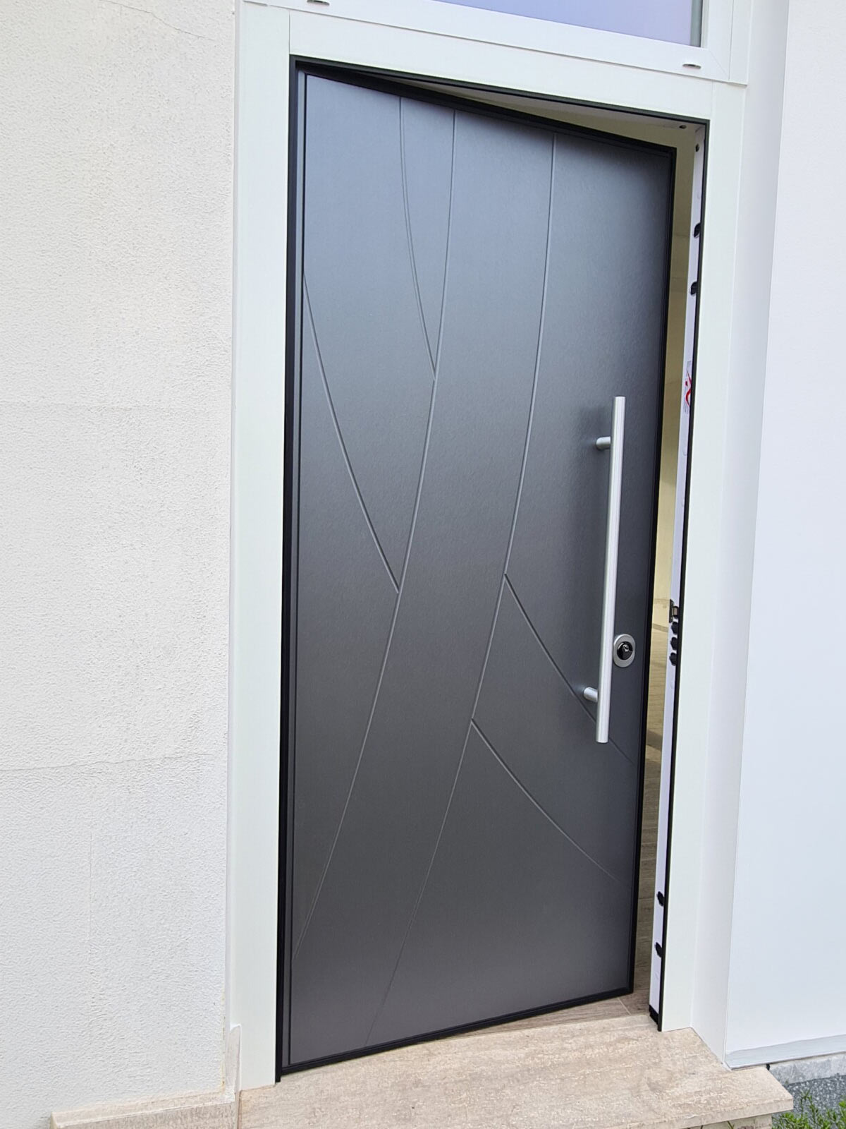 Porta blindata grigio antracite con incisioni geometriche diagonali e maniglione in acciaio