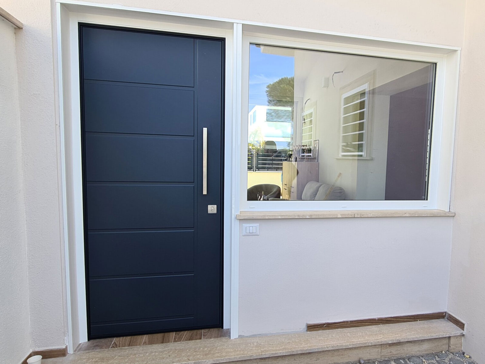 Elegante porta blindata scura con pannelli orizzontali integrata in un ingresso moderno