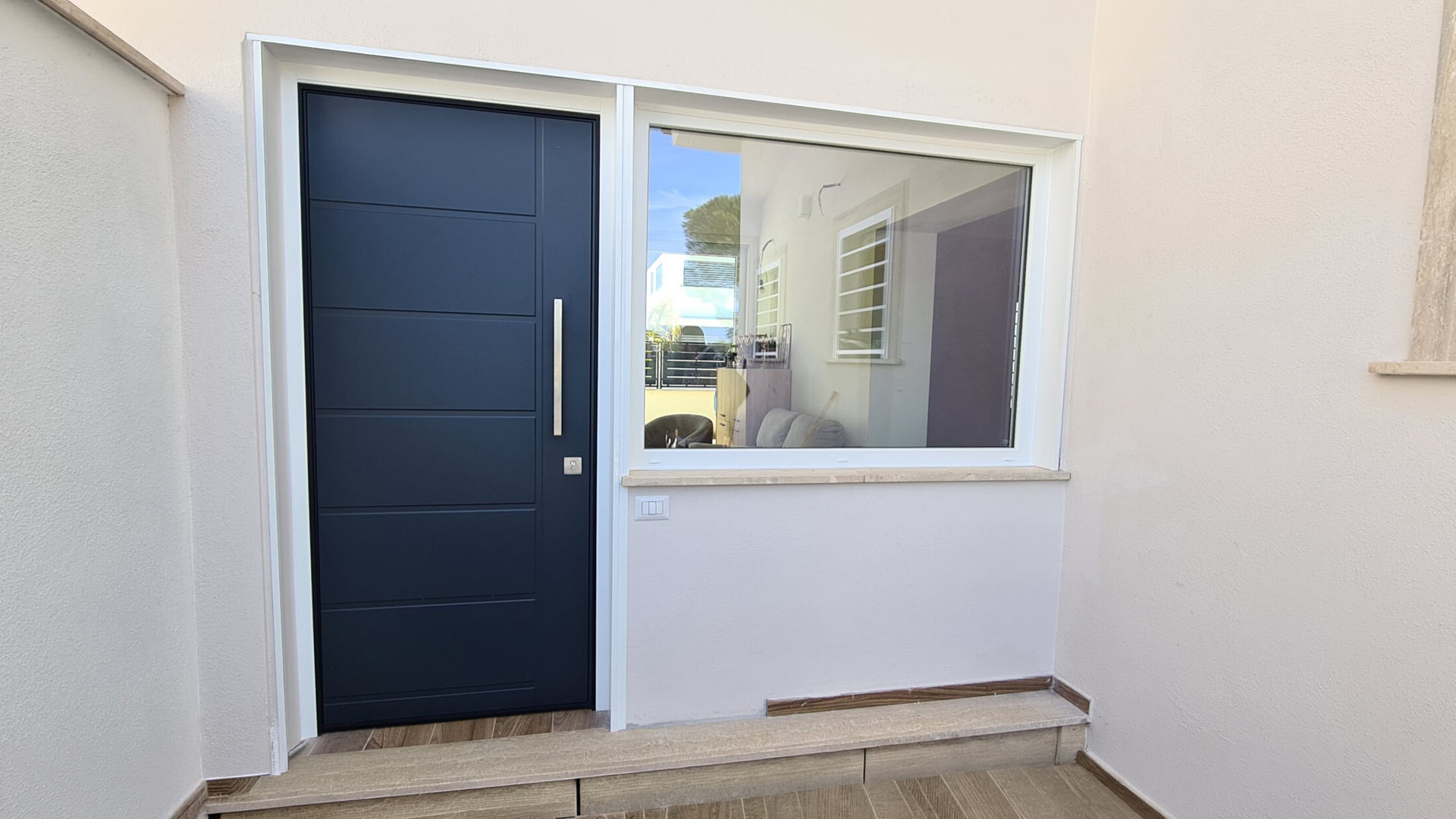 Elegante porta blindata scura con pannelli orizzontali integrata in un ingresso moderno