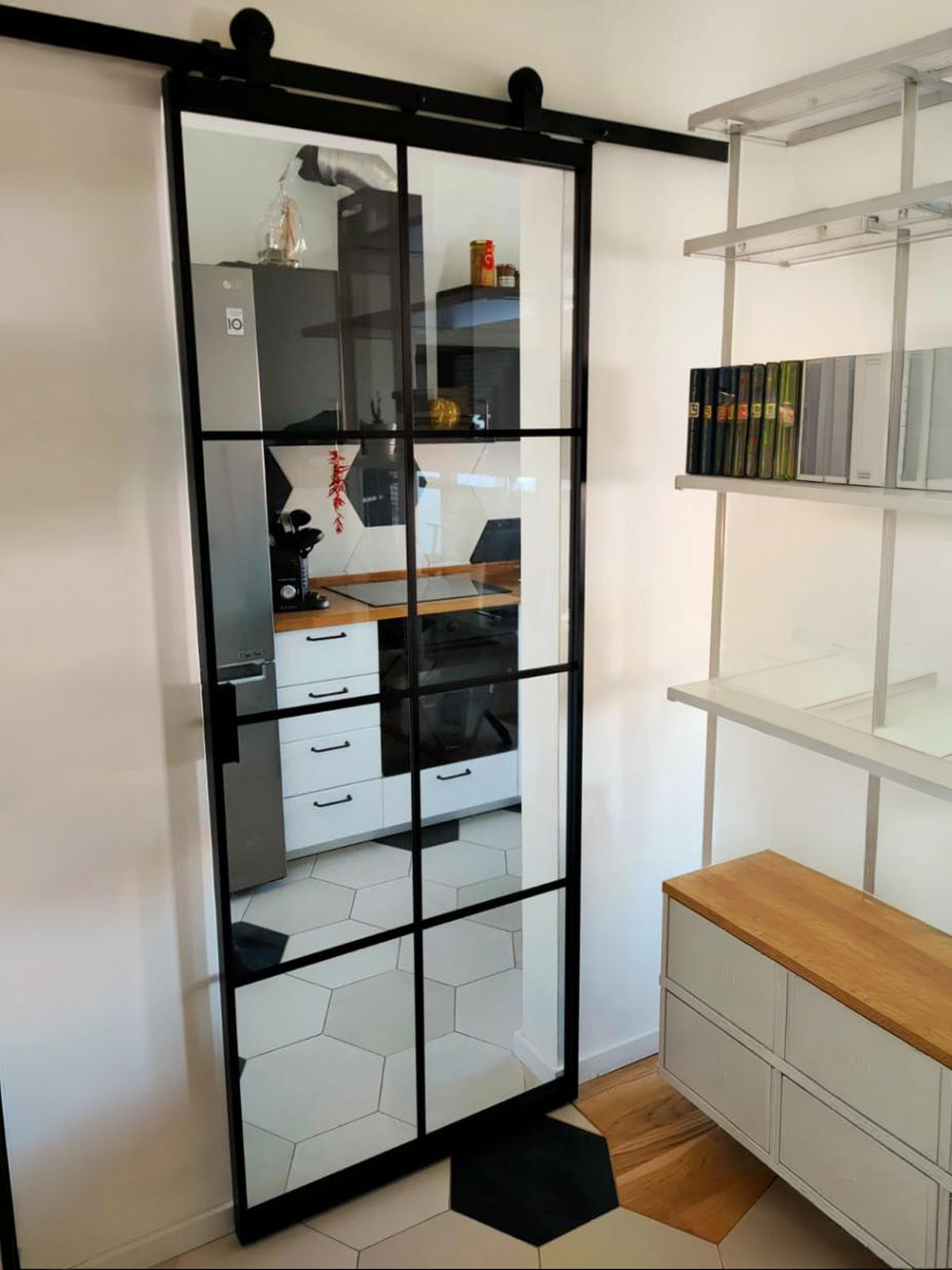 Porta scorrevole in vetro con telaio nero in stile industriale tra cucina e zona giorno
