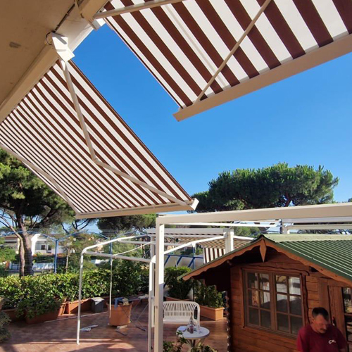 Struttura outdoor bianca chiusa con vetrate panoramiche scorrevoli su prato sintetico