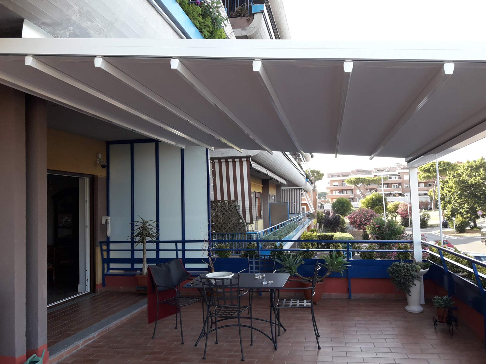 Ampio terrazzo protetto da una pergotenda su misura con struttura bianca e telo retrattile