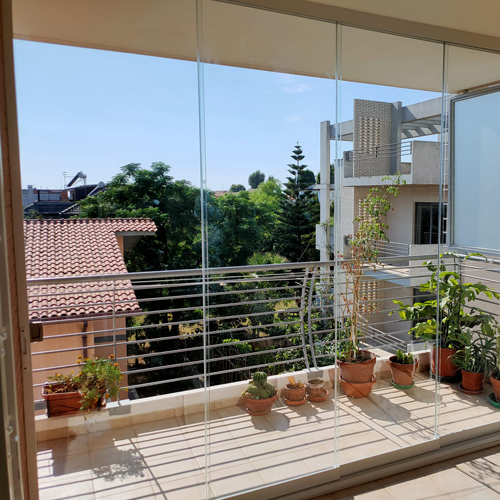 Balcone luminoso chiuso con vetrate panoramiche senza profili verticali dietro al parapetto in metallo