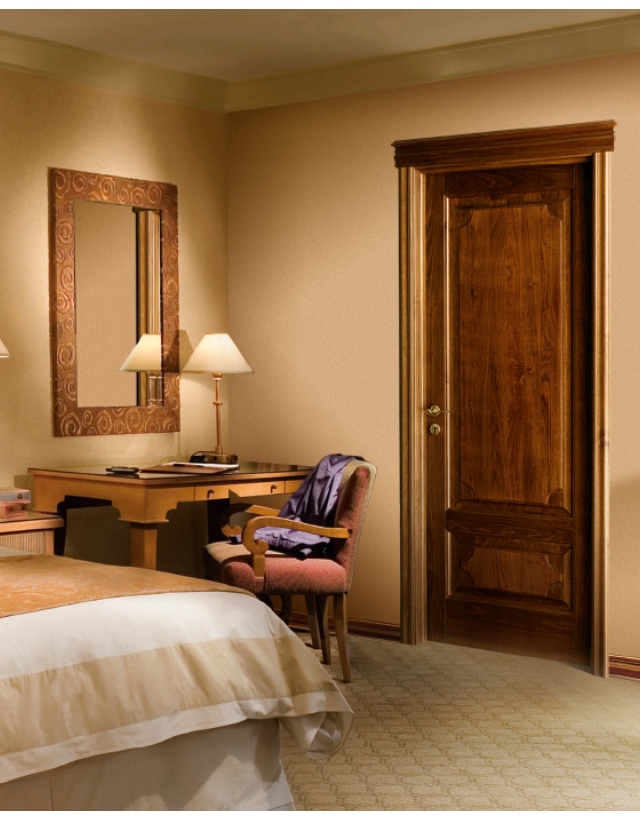 Raffinata camera da letto dallo stile classico con una pregiata porta d'interno a battente in legno massello lavorato.