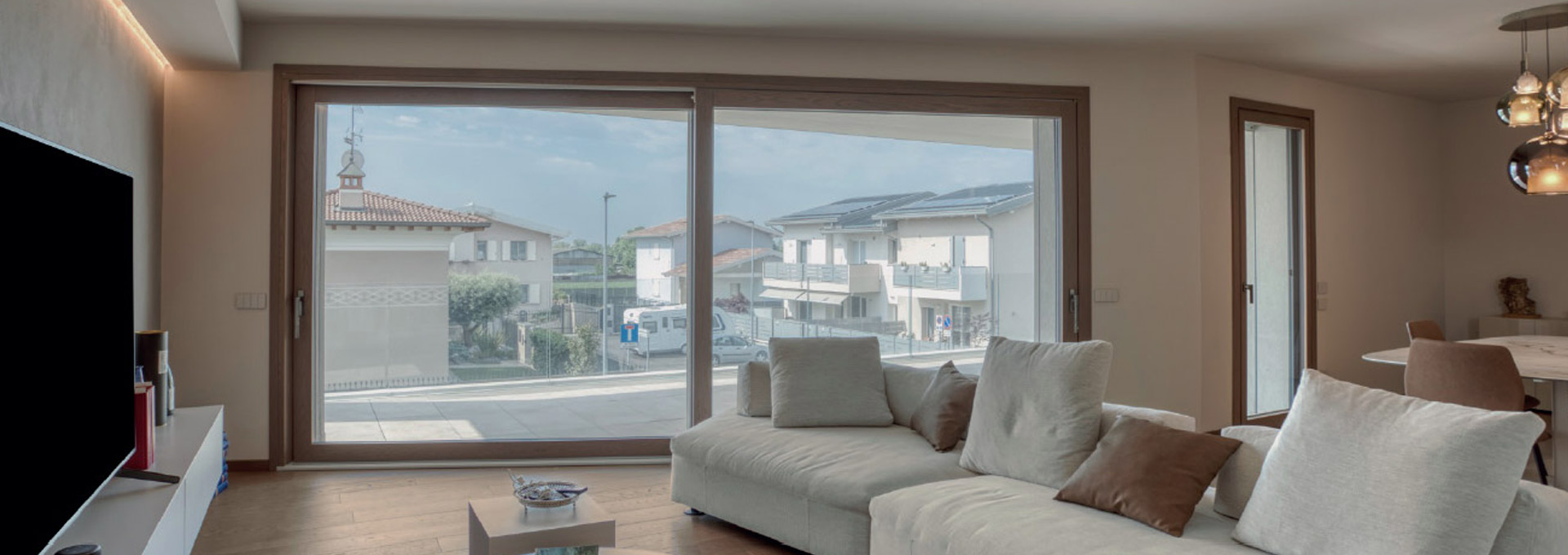Scorrevoli DMR Legno-Alluminio: calore naturale e isolamento termico Ampia vetrata scorrevole DMR in legno naturale installata in un soggiorno moderno, con vista panoramica esterna e profili ad alto isolamento.