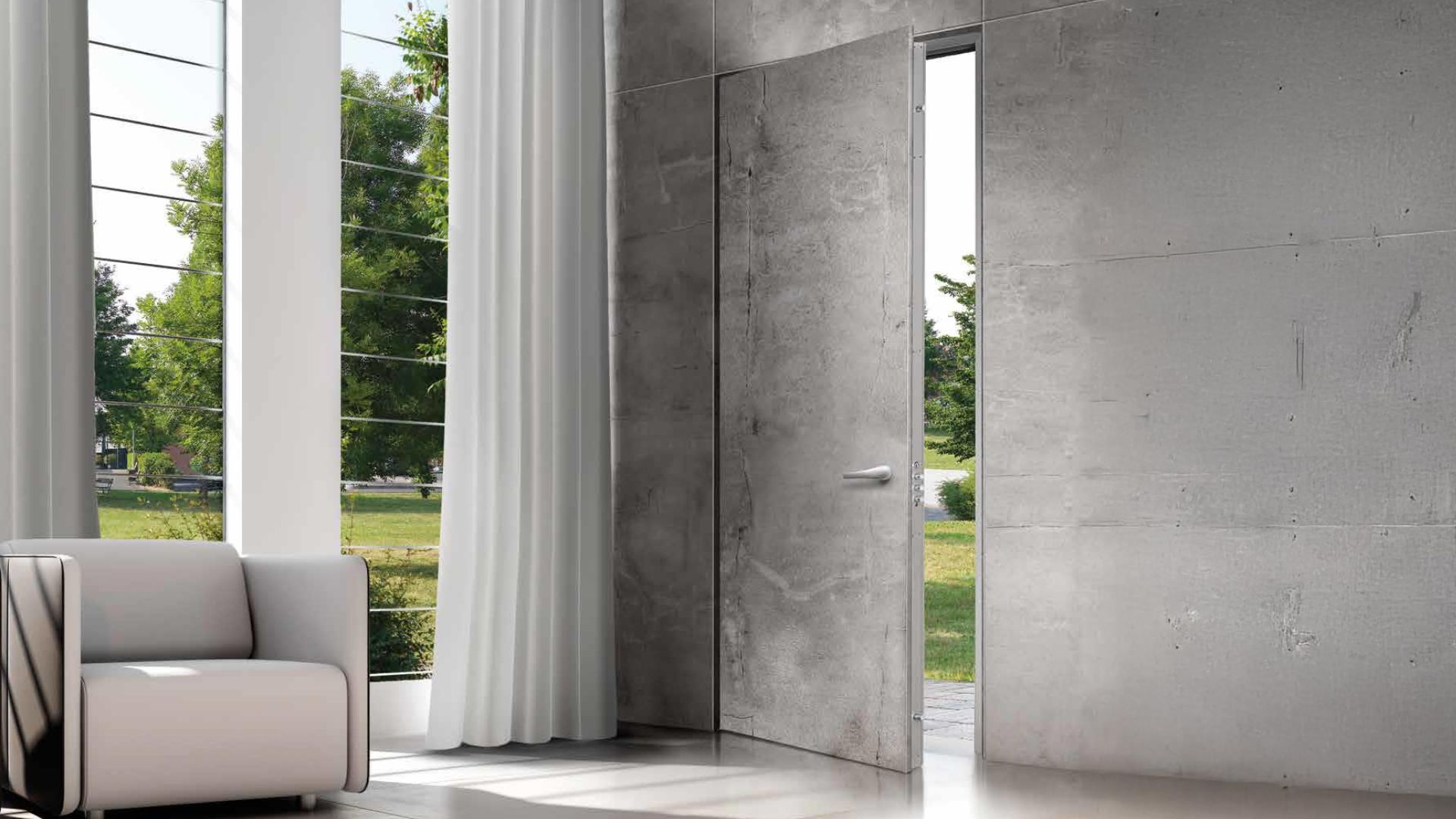 Elegante porta blindata Alias in versione filomuro con finitura grigia e maniglia di design, aperta su un giardino fiorito, con un moderno videocitofono visibile sulla parete interna.