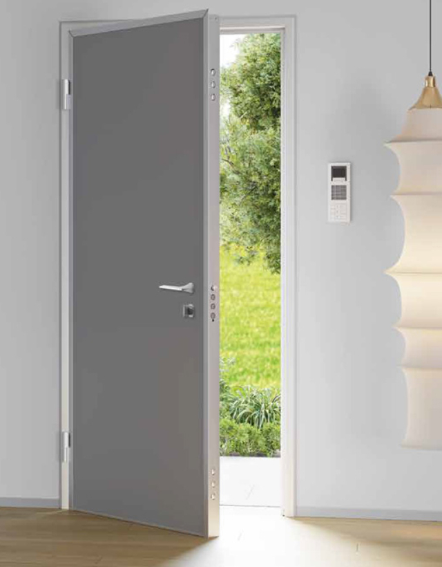 Dettaglio product Alias con interno di una porta blindata grigio antracite aperta, che mostra la serratura smart, i perni blindati antistrappo e l'elegante maniglia in acciaio, in un salotto contemporaneo illuminato da lampade di design accese.