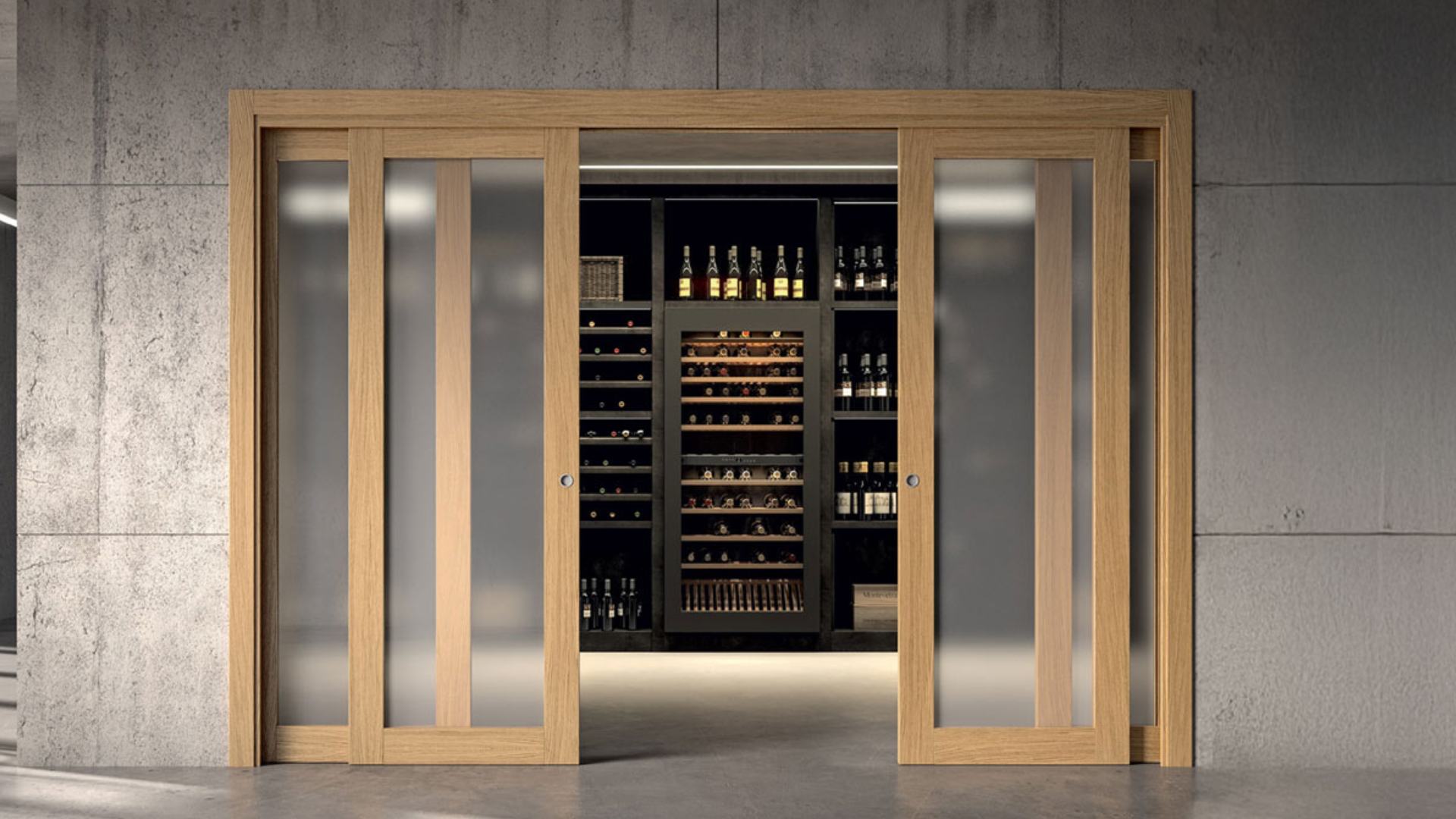Ambiente moderno in cemento con doppia porta scorrevole a scomparsa GD Dorigo in legno chiaro e inserti in vetro opaco, che separa un salone da una lussuosa cantina vini.